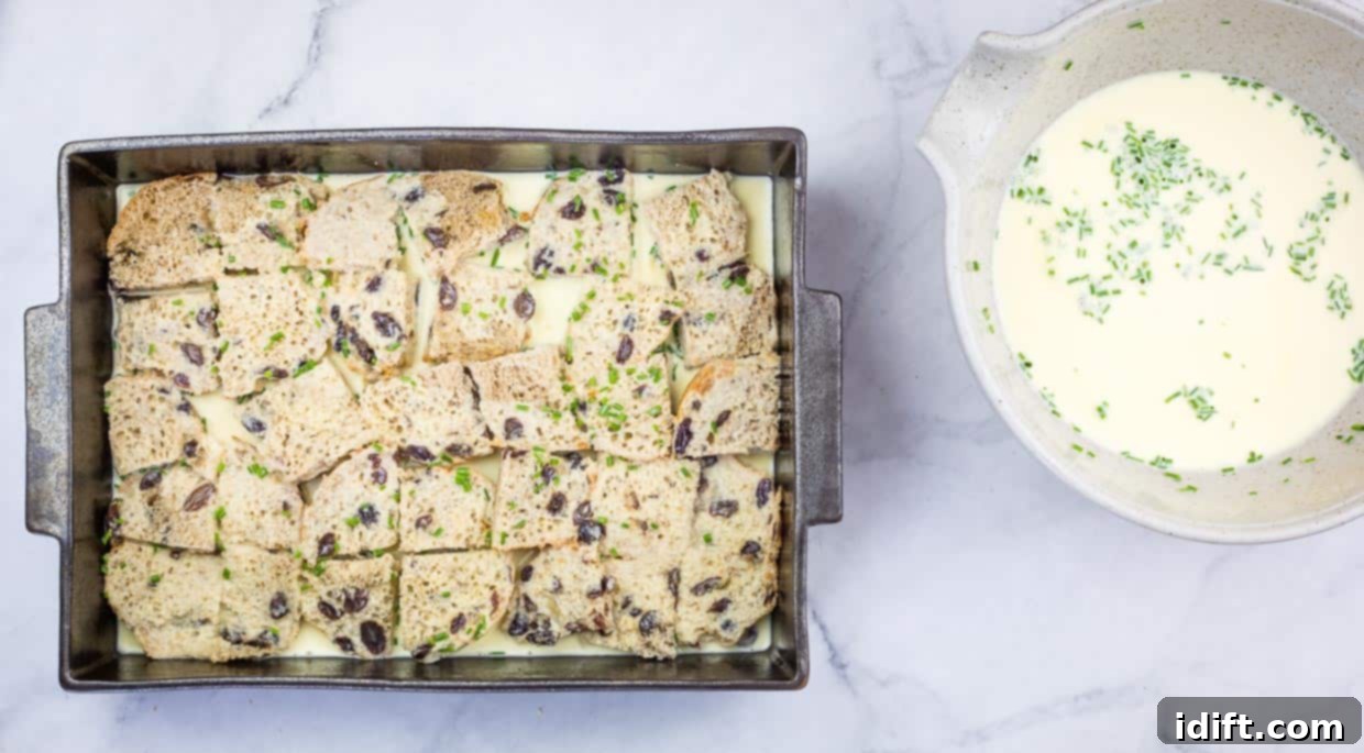 Spiced Hot Cross Bun French Toast Bake 8 Bottom layer of buns in the dish with egg custard on top.