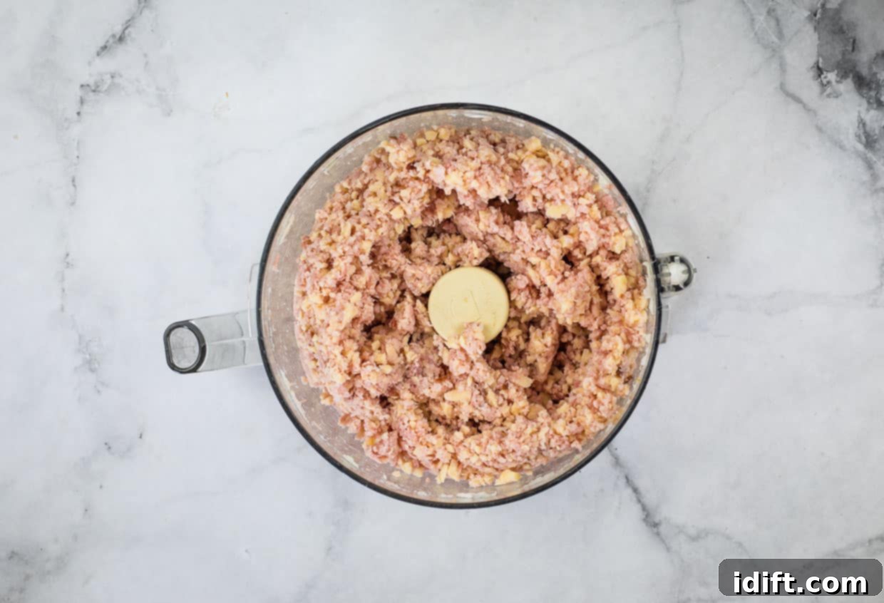 Ham, cheese, and onion in a food processor bowl.