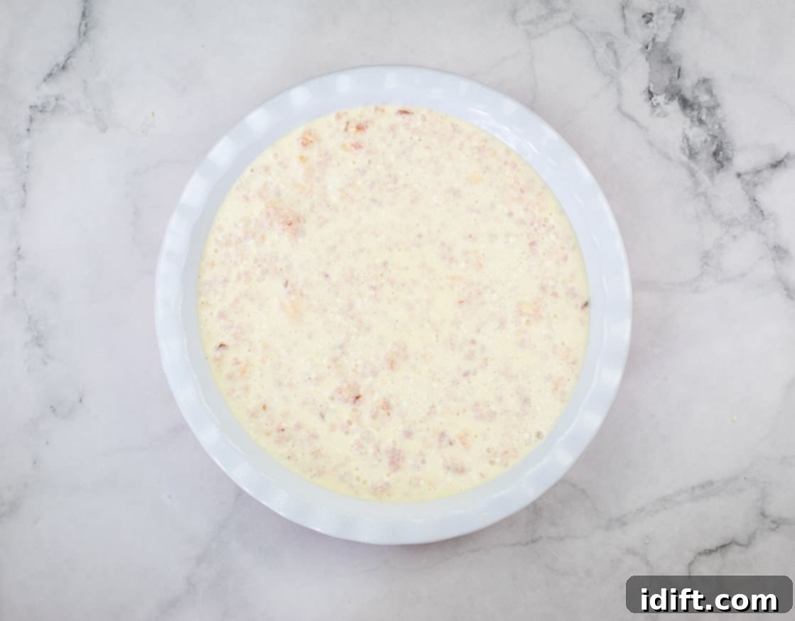 Custard on top of the ham mixture in a pie dish.