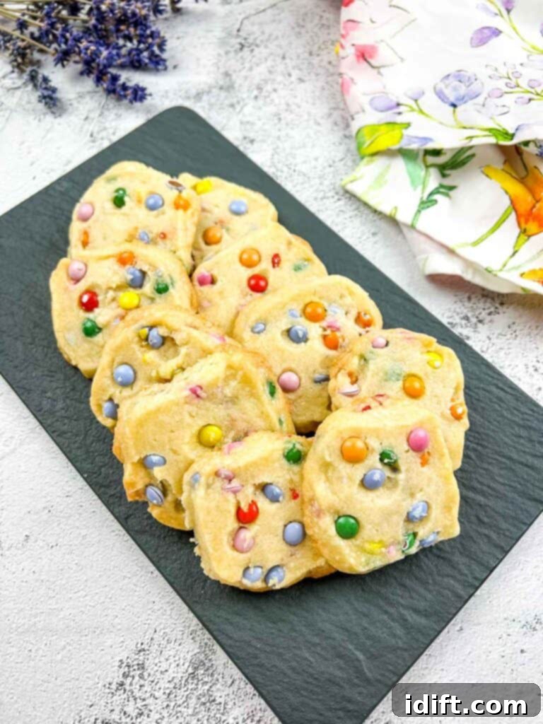 Spring Blossom Shortbread with Cheerful Candy Drops 2 Easter shortbread cookies with mini m&ms on a black plate, showcasing their vibrant colors and crisp texture.