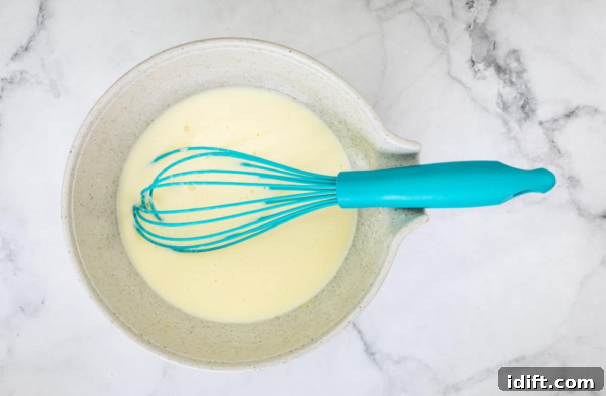 Sausage Pancake Poppers 9 Mixed wet ingredients in a bowl, being whisked to combine.