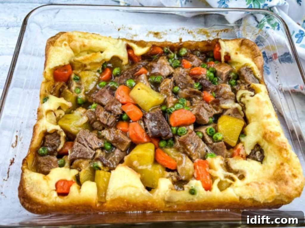 A close-up view of the Leftover Roast Beef Yorkshire Pudding Pie, freshly baked and golden brown in a ceramic baking dish.