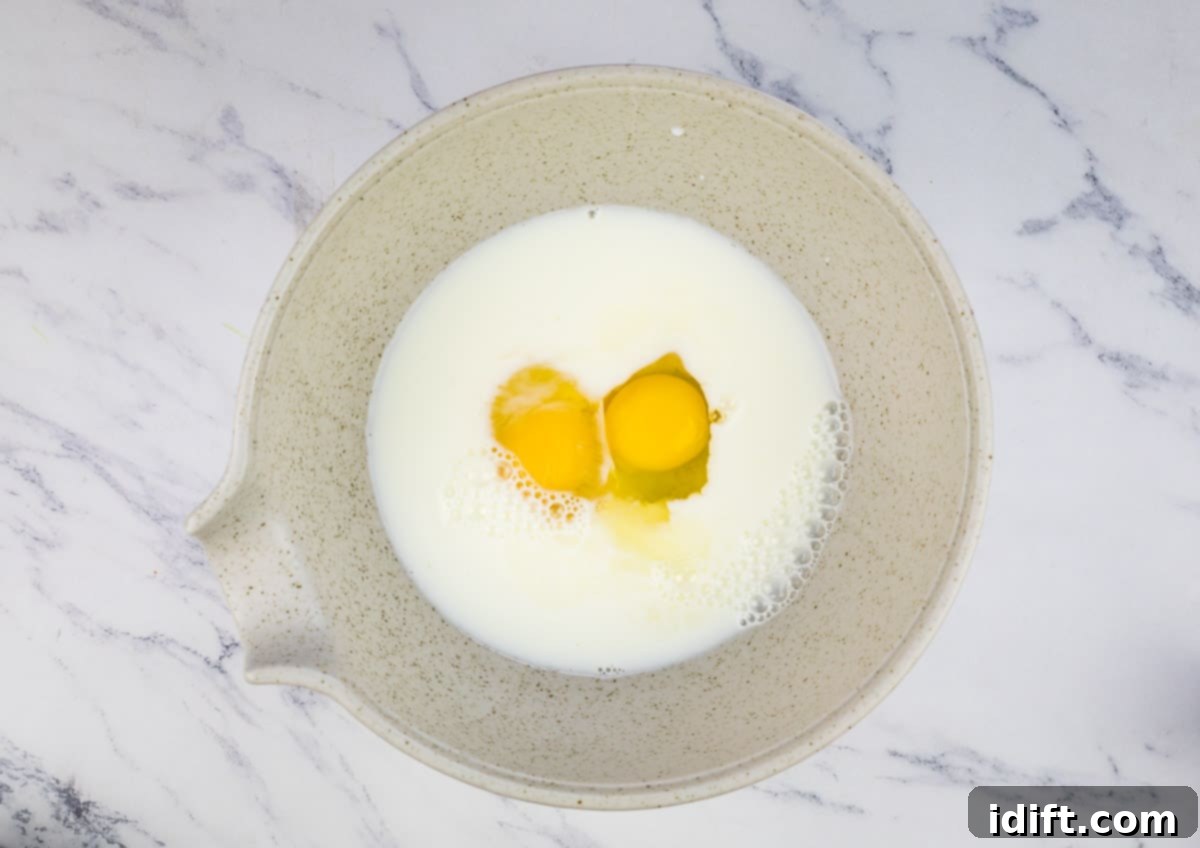 A bowl with eggs and milk being whisked together, forming the base for the Yorkshire pudding batter.