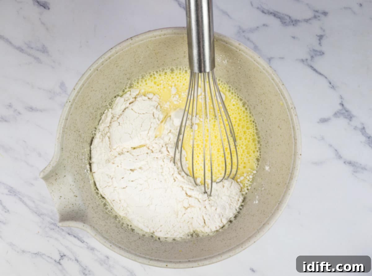 Flour being added to the egg and milk mixture in a bowl, destined to become the airy Yorkshire pudding batter.