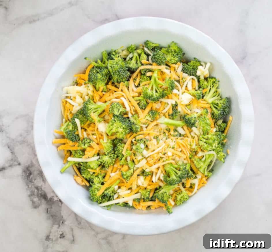 Impossible Broccoli Three-Cheese Quiche 8 A large bowl containing mixed broccoli, cheddar cheese, mozzarella cheese, and chopped onion, tossed together.