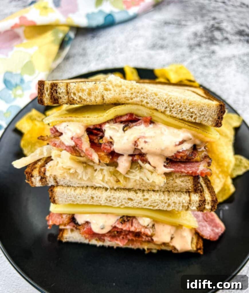 A stacked Pastrami Reuben Sandwich on a black plate.