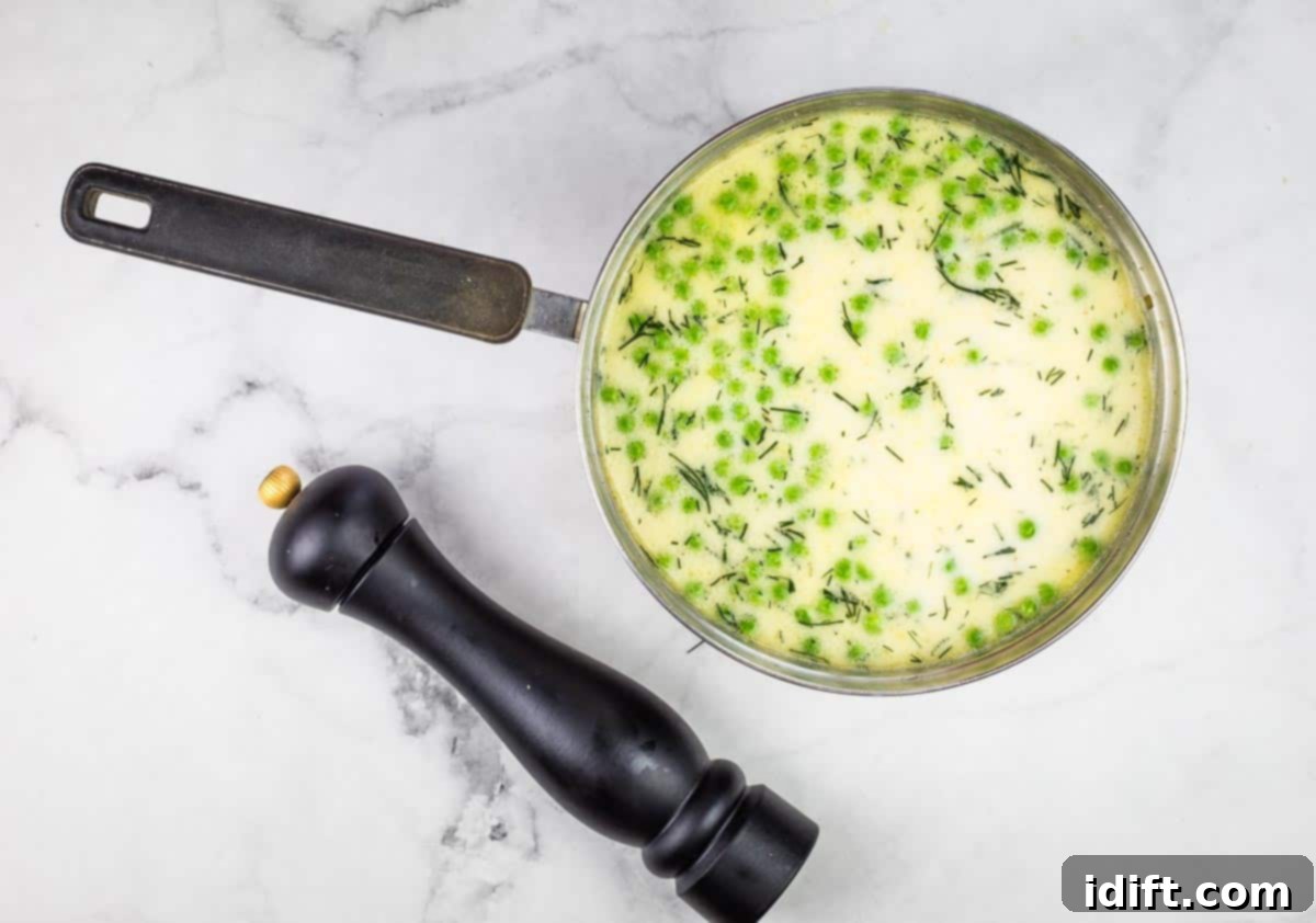 Potato and Green Pea Chowder 10 Cream and vibrant green peas being stirred into the simmering soup.