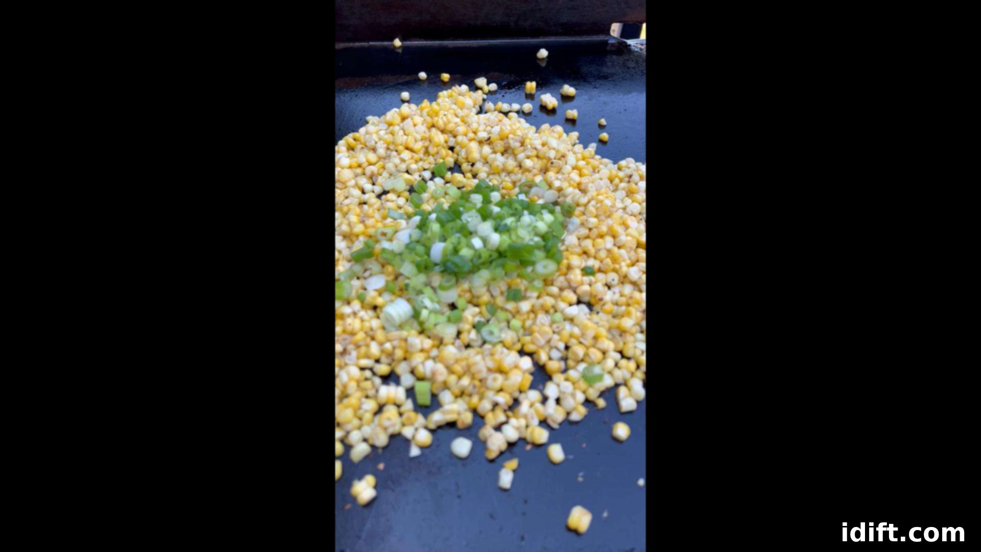 Blackstone's Sizzling Bacon Corn 9 Green onions and minced garlic being added to the corn on the griddle.