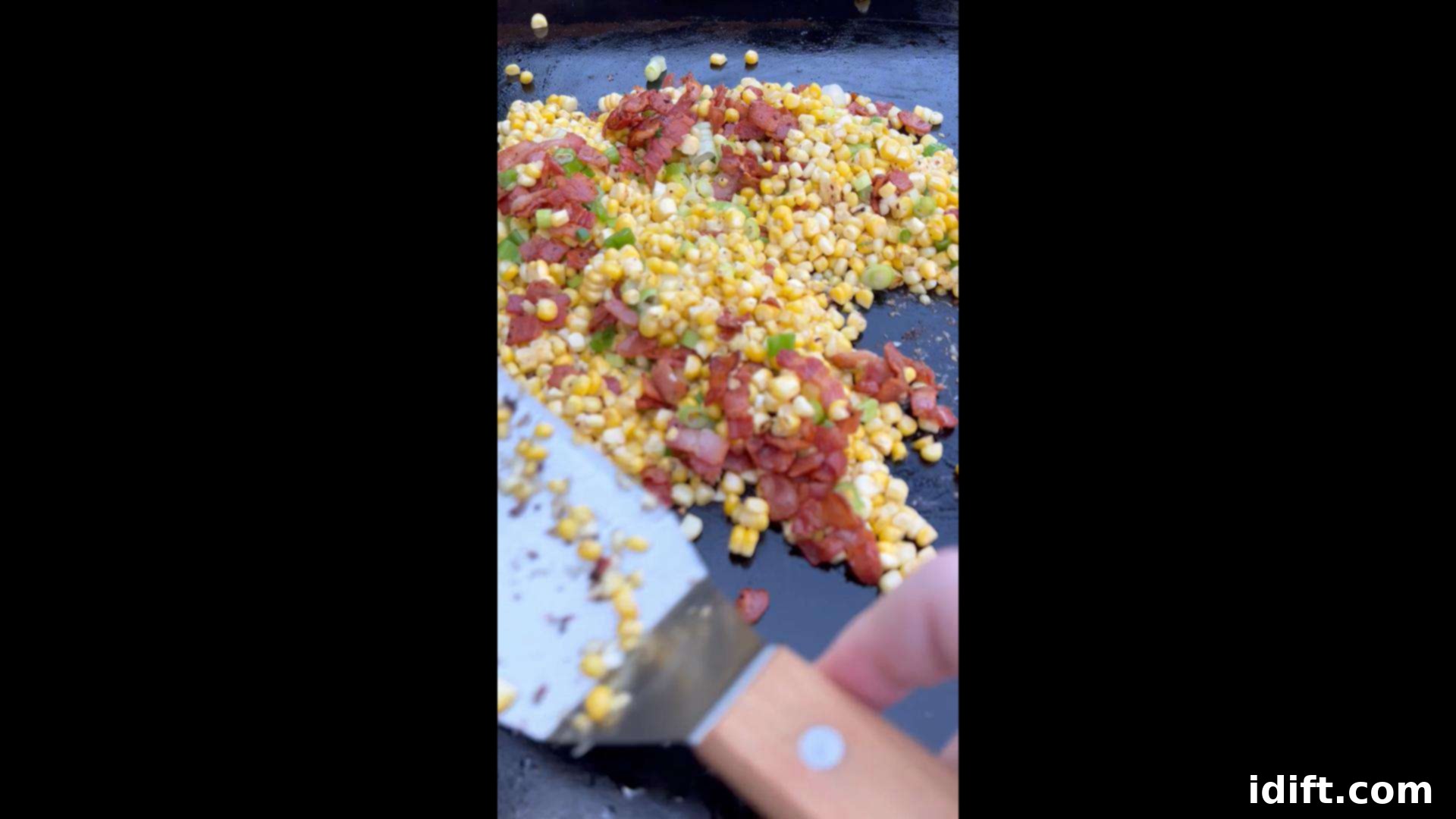Blackstone's Sizzling Bacon Corn 10 Cooked bacon being mixed back into the corn on the griddle.