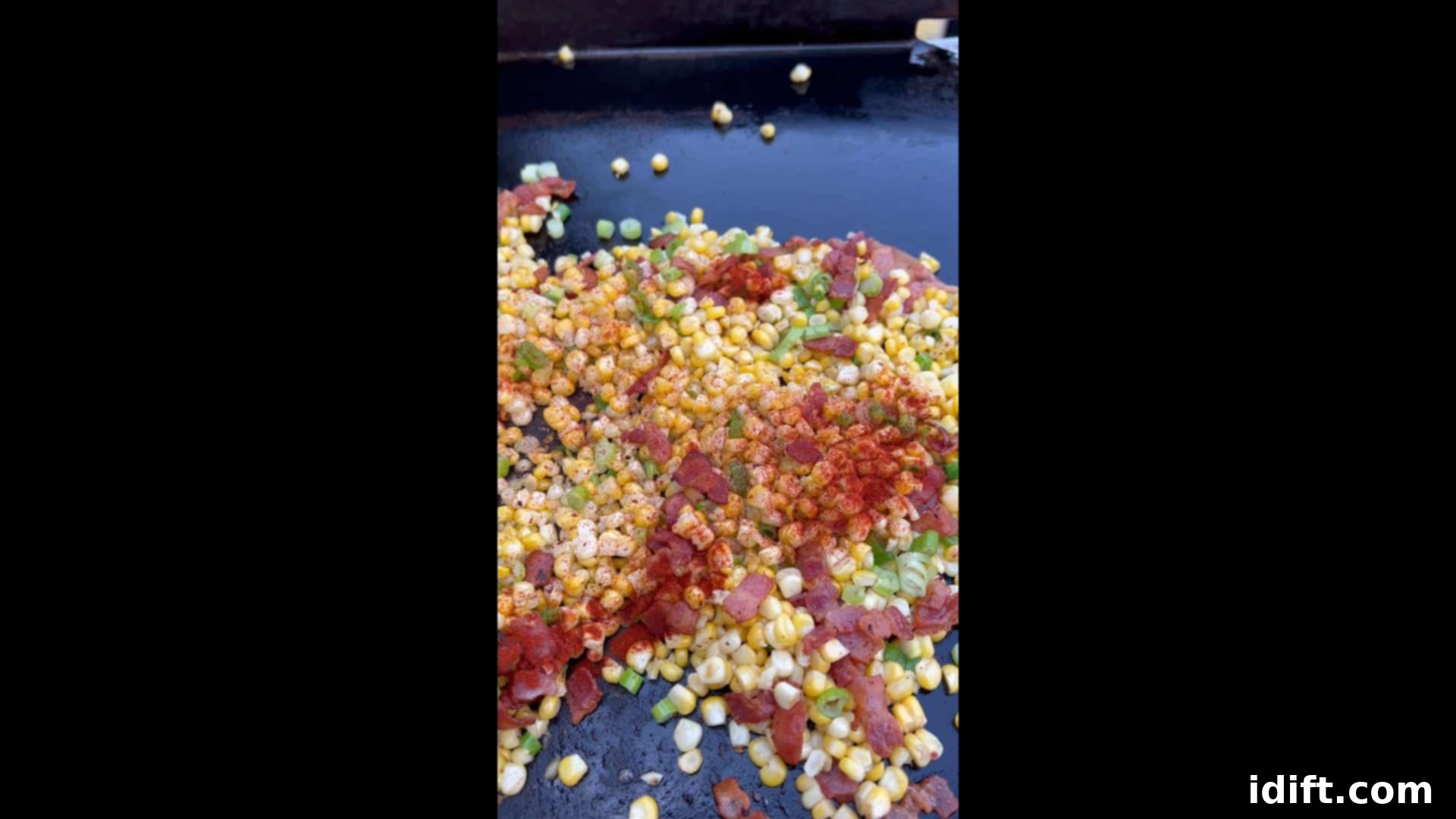 Blackstone's Sizzling Bacon Corn 11 Seasoning (paprika, salt, and pepper) being added to Bacon-Fried Corn on the griddle.