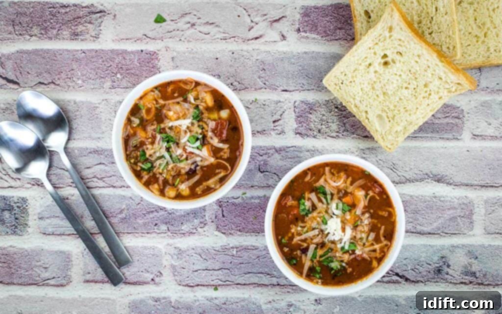 A top-down shot of two bowls of steaming Pasta e Fagioli Soup, accompanied by crusty bread.