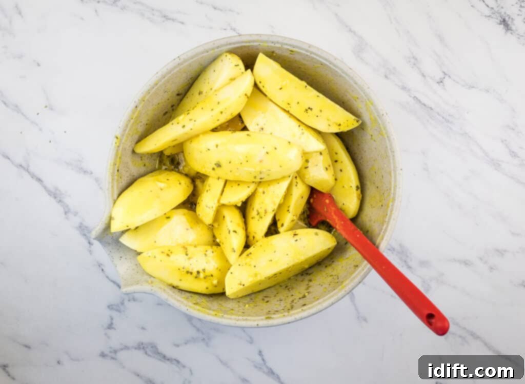 Potatoes tossed with dressing in a bowl.