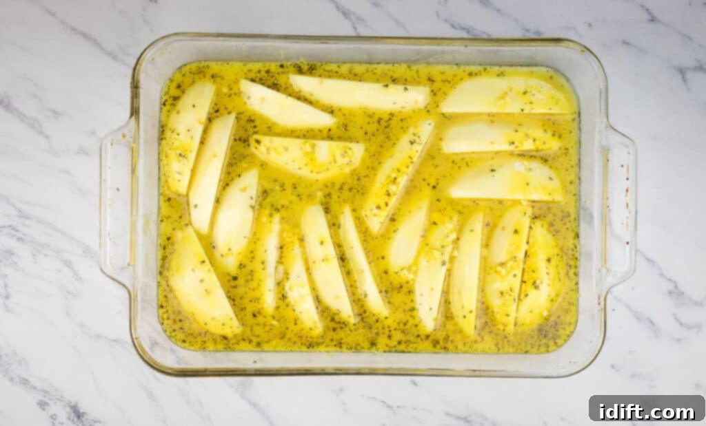 Potatoes in a baking dish with chicken broth.