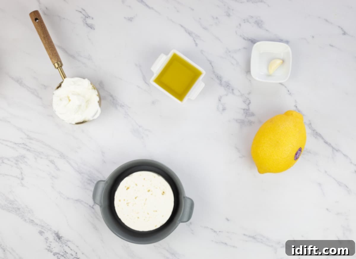 The specific ingredients required for preparing the whipped feta, including a block of feta cheese, Greek yogurt, olive oil, garlic, and lemon.