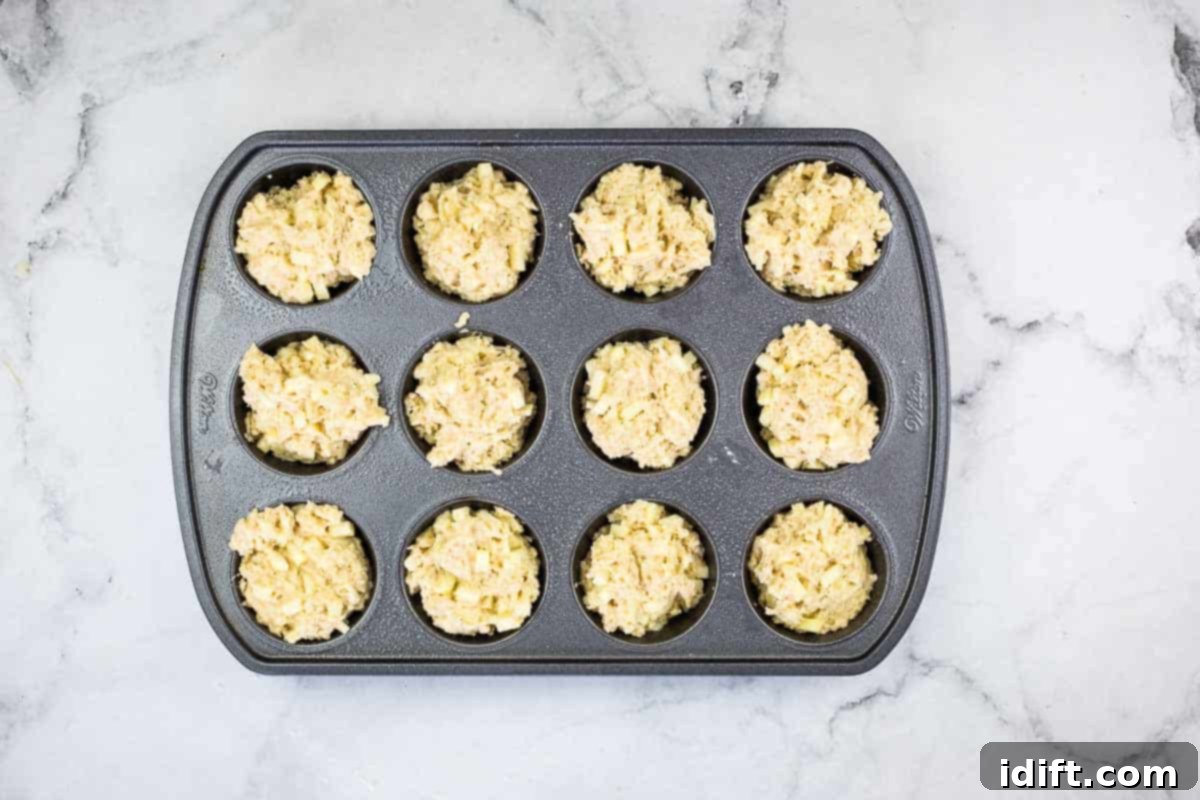 A muffin tin with all its cups filled with batter, perfectly poised for baking.