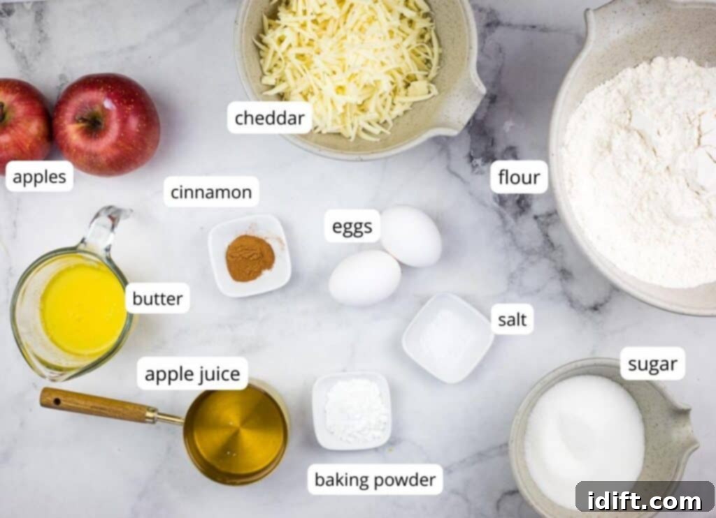 Carefully arranged ingredients for making Apple Cheddar Muffins, including flour, sugar, baking powder, salt, cinnamon, shredded cheddar, eggs, apple juice, melted butter, and diced apples.