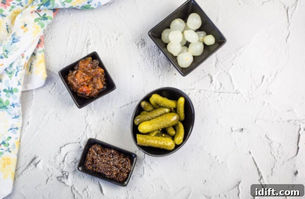 A selection of colorful pickles, gourmet spreads, and condiments arranged in small bowls for a charcuterie board.