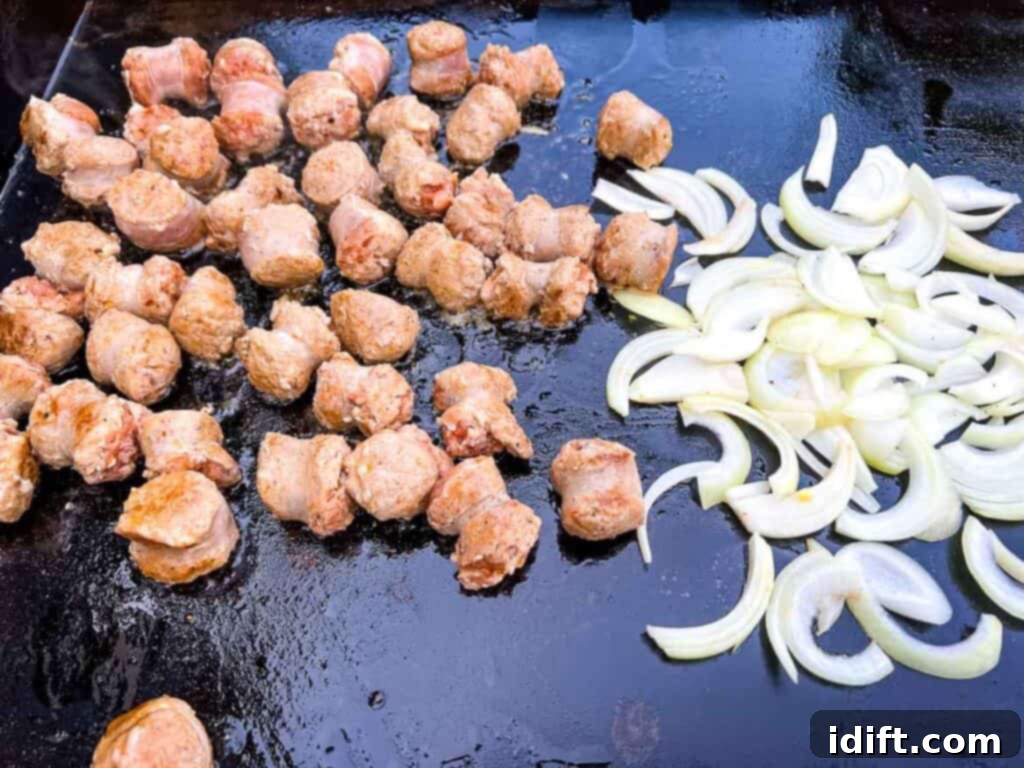 Onions softening alongside cooking sausage on the griddle.