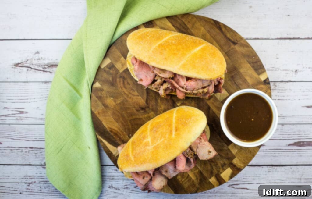 A horizontal top-down shot of 2 Smoked French Dip Sandwiches on a board.