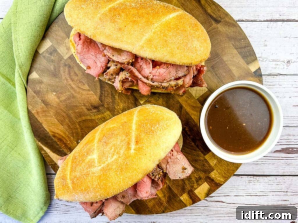 A top down shot of 2 Smoked French Dip sandwiches on a board with jus.