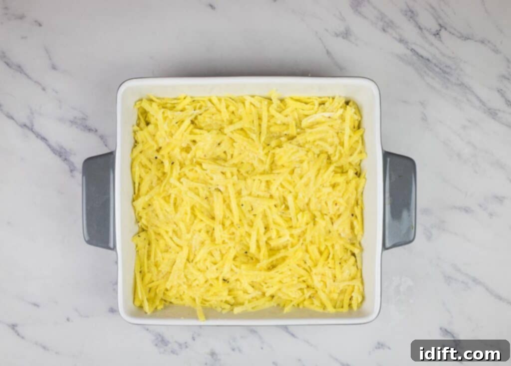 The potato mixture spread evenly in the bottom of a casserole dish.