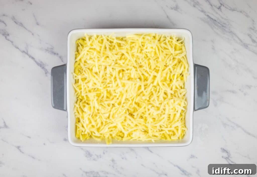 Shredded Jarlsberg cheese layered on top of the potato mixture.