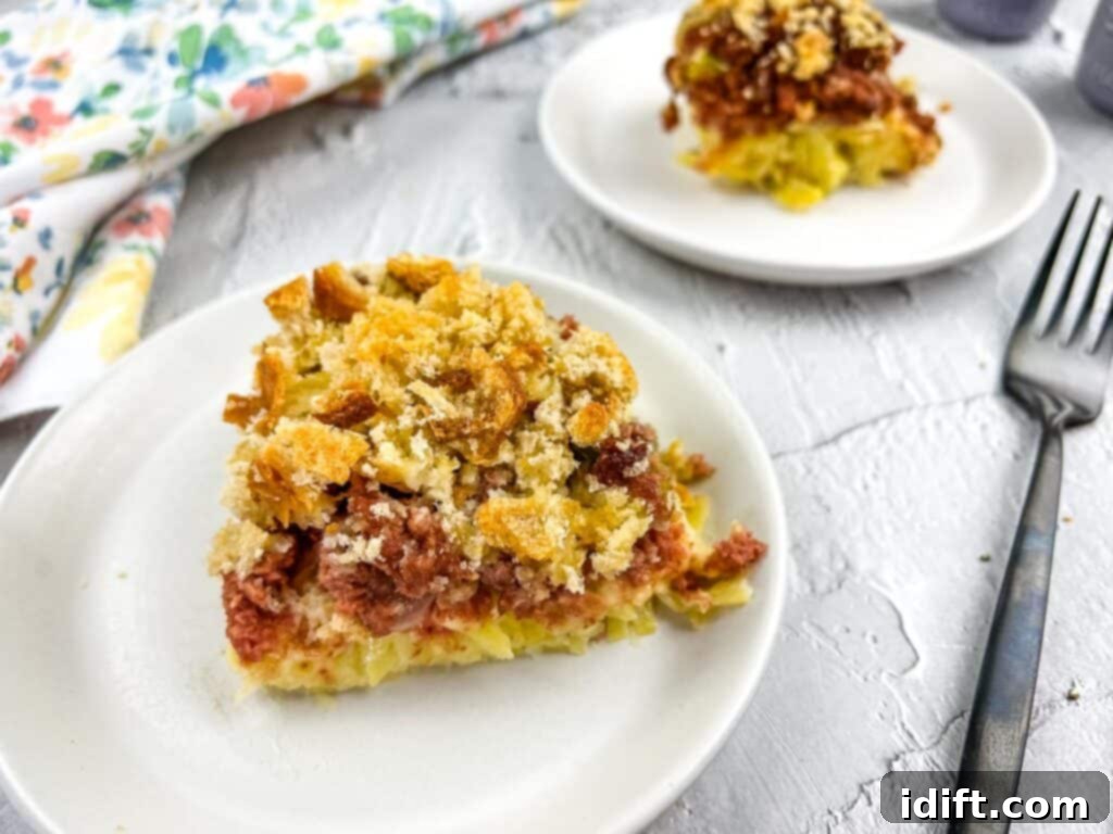 Hearty Corned Beef Hash Bake 3 A perfectly sliced portion of Canned Corned Beef Hash Casserole on a white plate, ready to be enjoyed.