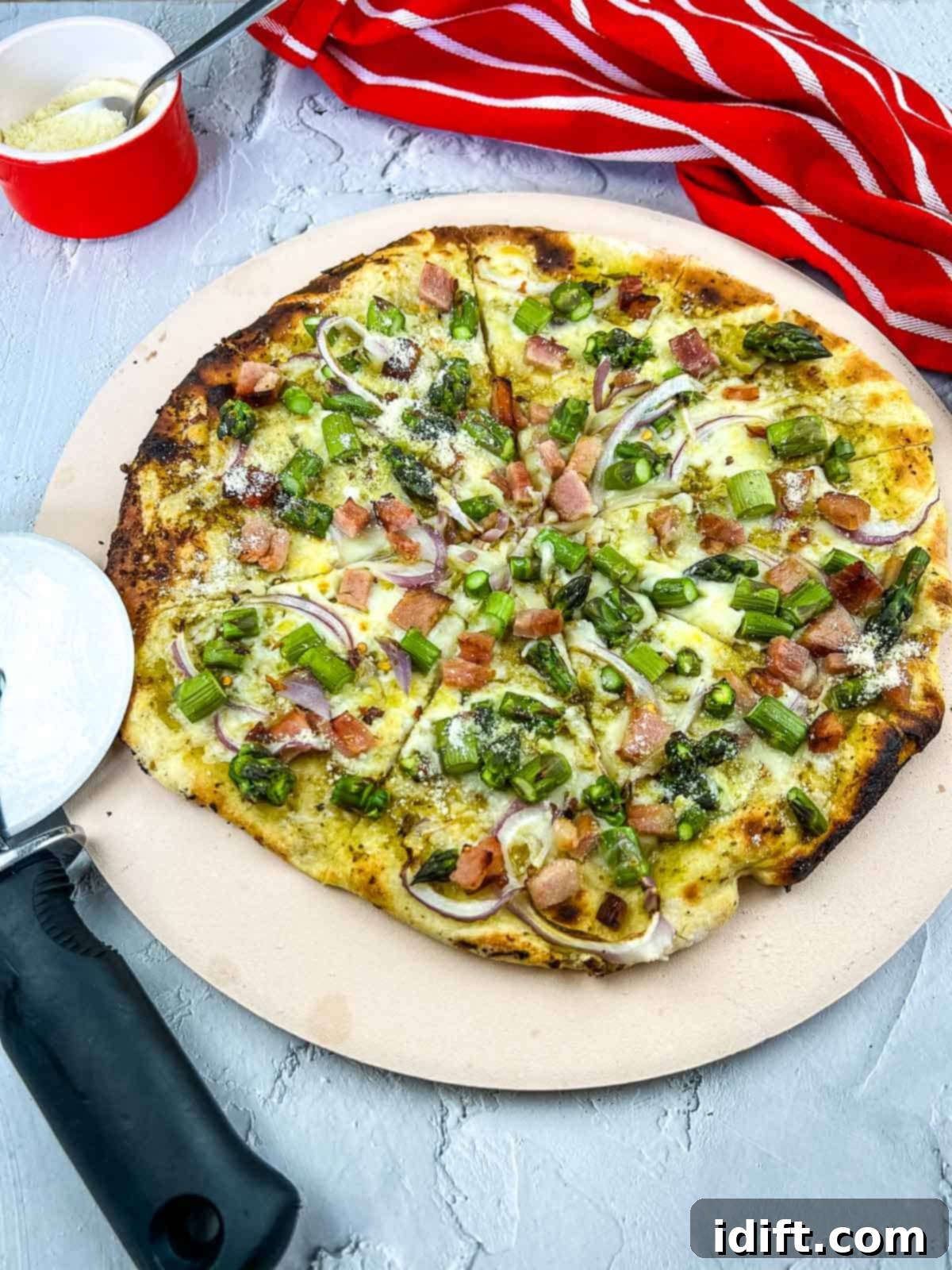 Asparagus and Prosciutto Masterpiece 2 Vertical image of a freshly baked Ham and Asparagus pizza on a pizza stone, showcasing a golden crust and vibrant toppings.