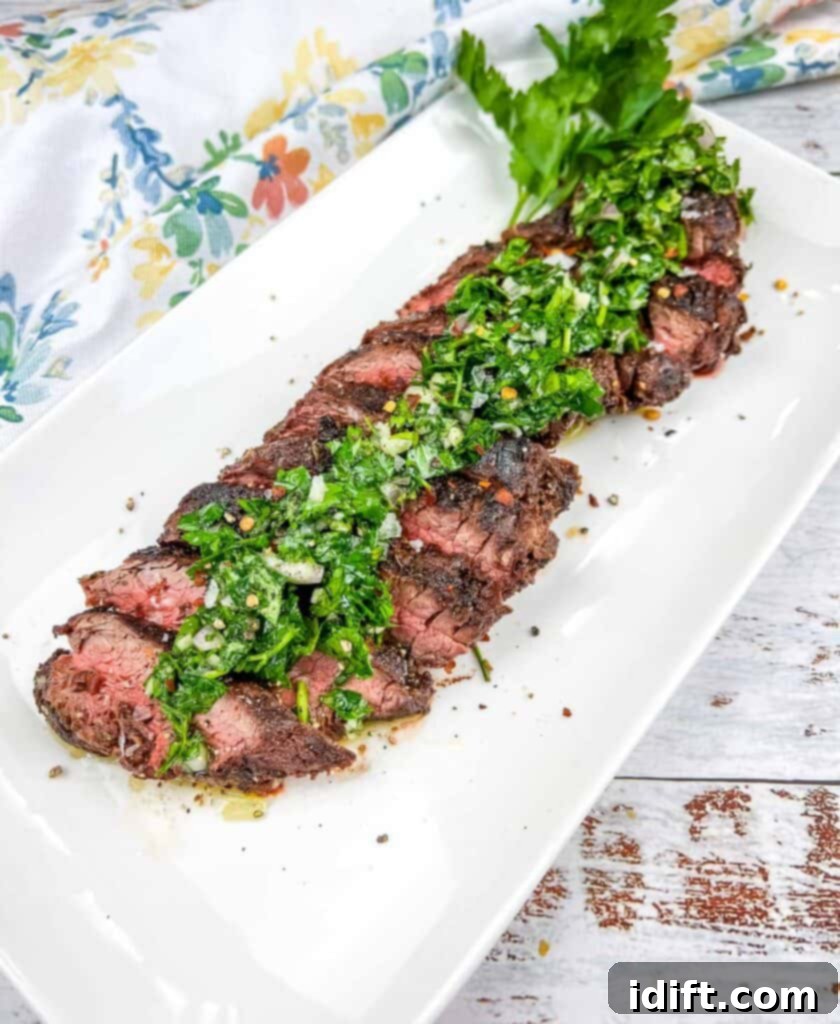 Tender Hanger Steak with Bright Chimichurri 2 Grilled Hanger Steak with Chimichurri on a white platter, garnished with fresh herbs.