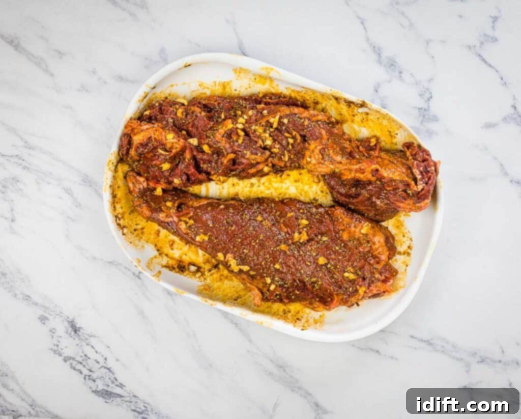Tender Hanger Steak with Bright Chimichurri 9 Hanger steaks being rubbed with the spice blend on a plate.