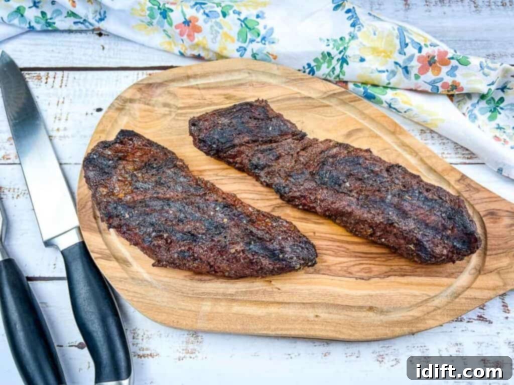 Tender Hanger Steak with Bright Chimichurri 12 Grilled steaks resting on a wooden cutting board after being removed from the grill.
