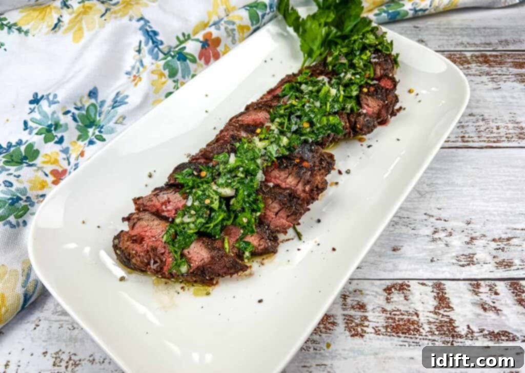 Tender Hanger Steak with Bright Chimichurri 3 Sliced grilled hanger steak with a generous dollop of green chimichurri sauce on a platter, ready to serve.