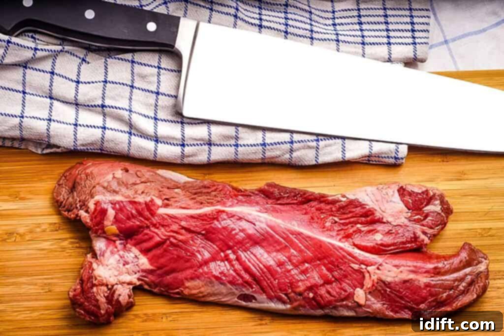 Tender Hanger Steak with Bright Chimichurri 4 An untrimmed hanger steak on a cutting board next to a sharp knife, showing the membrane.