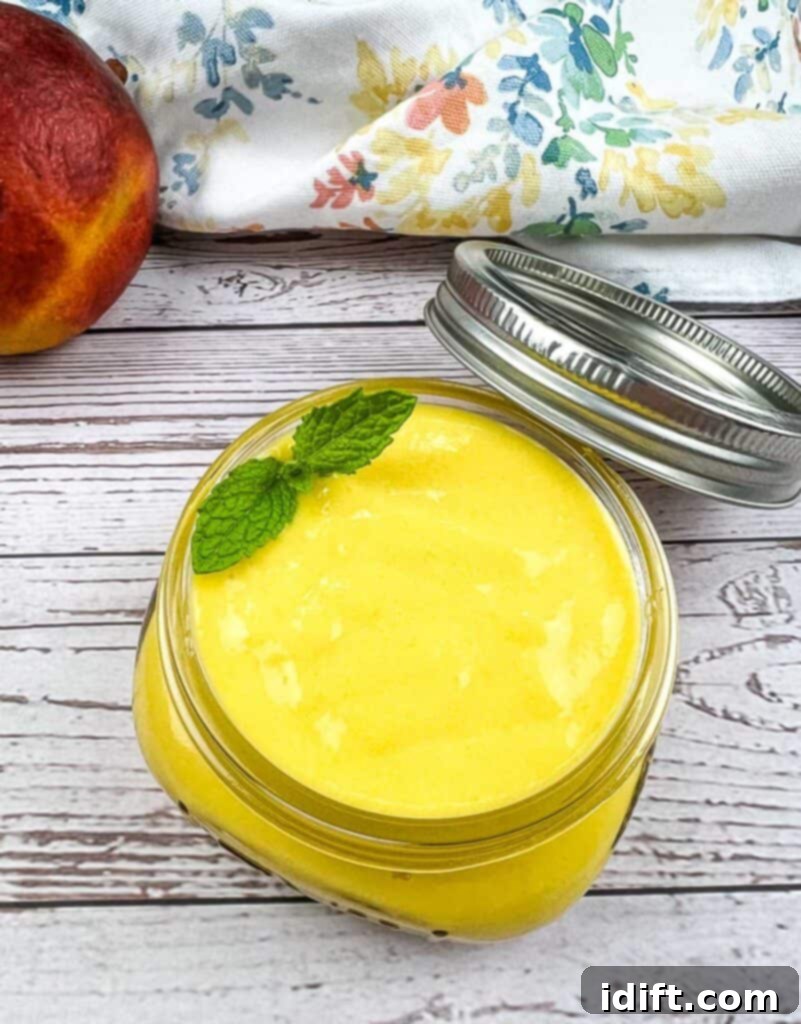 A jar of bright yellow mango curd with a lid, sitting on a rustic surface.