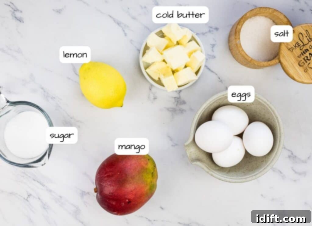 Carefully arranged ingredients for mango curd: diced mangoes, granulated sugar, fresh lemons, whole eggs, and a stick of butter.