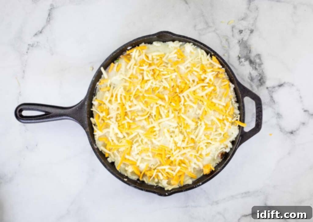 The dish topped with shredded cheddar cheese, ready for baking.
