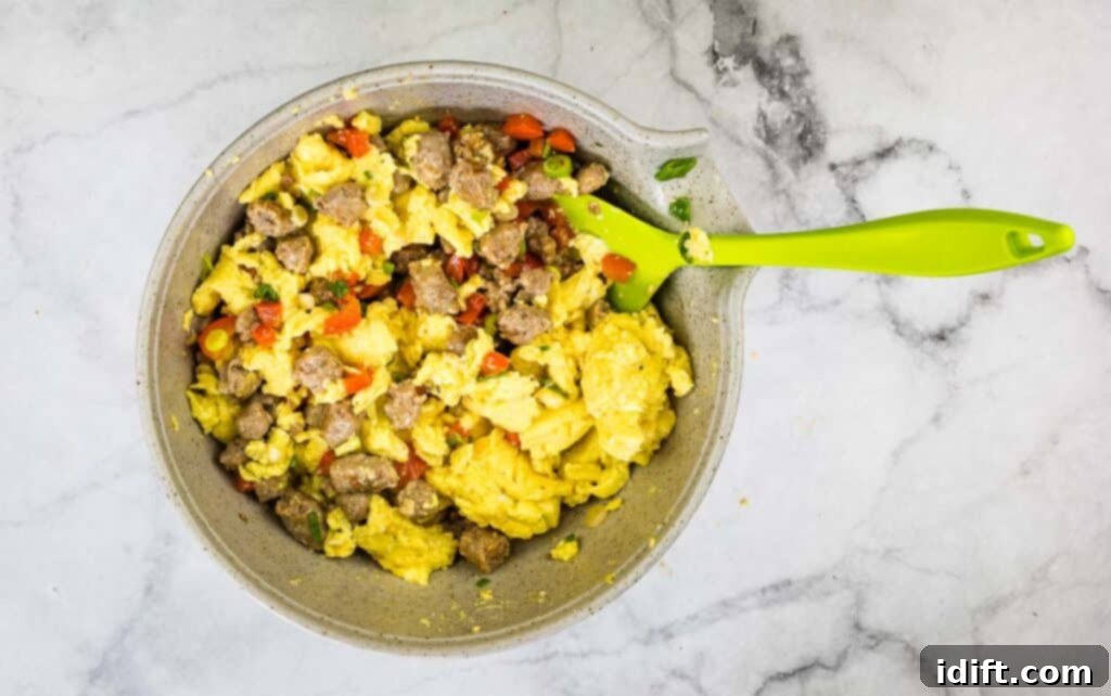 Cooked eggs and sausage mixed in a bowl.
