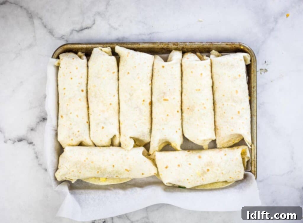 Rolled burritos on a baking sheet ready for freezing.