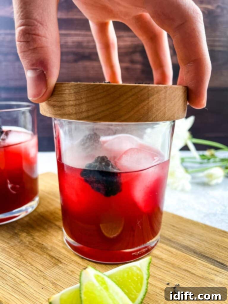 The smoking plate is removed from a Smoked Blackberry Margarita, revealing the ready-to-enjoy cocktail.