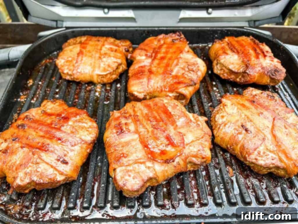 Elevate Your BBQ The Ninja Woodfire Grill's Smoky Sensation 3 Bacon wrapped burgers on an open Ninja Woodfire Grill.