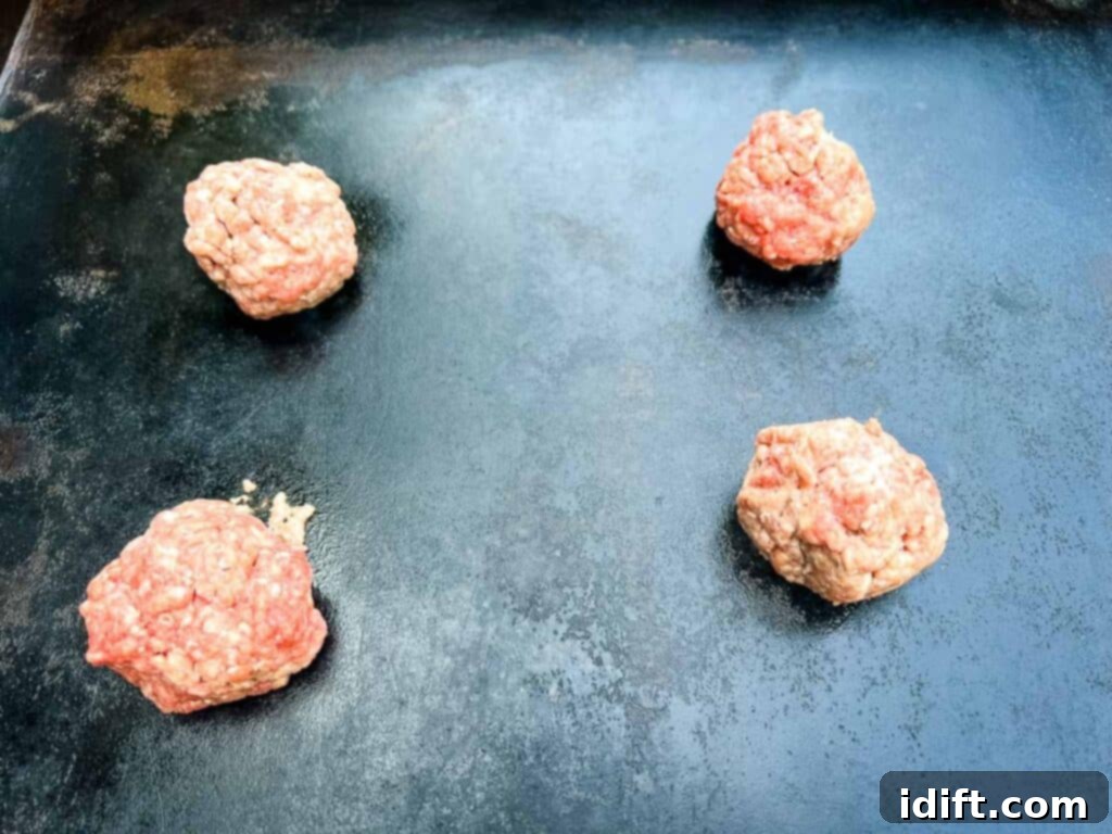 Griddle Gold: The Art of the Blackstone Smash Burger 10 Meat balls sizzling on a preheated hot griddle surface.