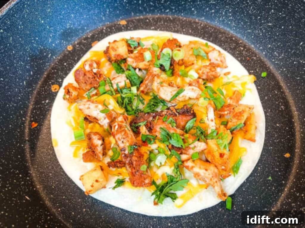Cooked Al Pastor chicken, green onions, and cilantro are added on top of the cheese-covered tortilla.