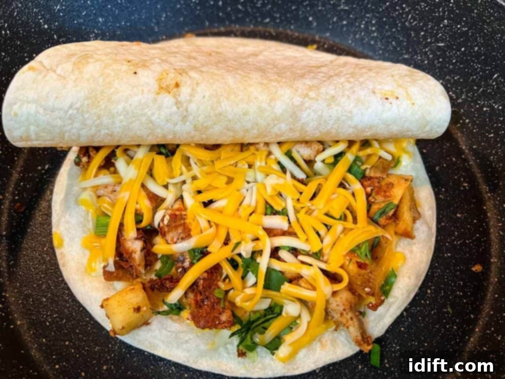 A final layer of cheese is added, followed by the second tortilla, completing the quesadilla assembly in the skillet.