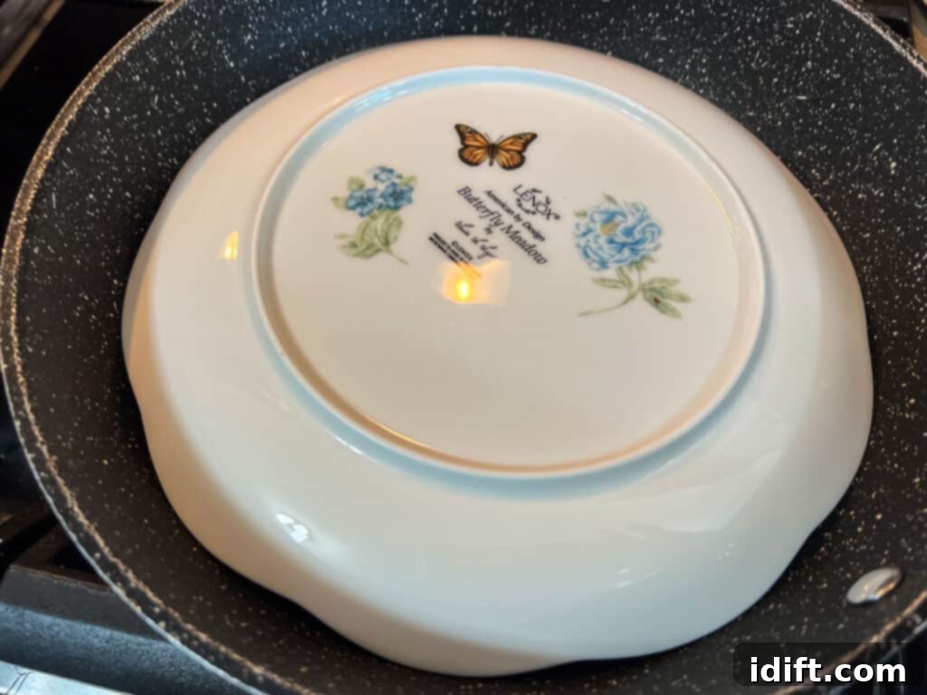 A plate placed over the cooking quesadilla in the skillet, ready for inversion to cook the other side.