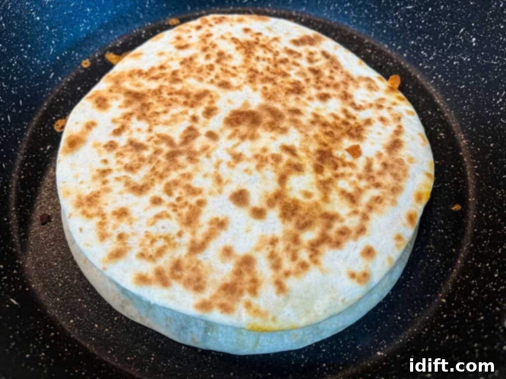 A perfectly cooked Chicken Al Pastor Quesadilla, golden brown and crispy, resting in a skillet.