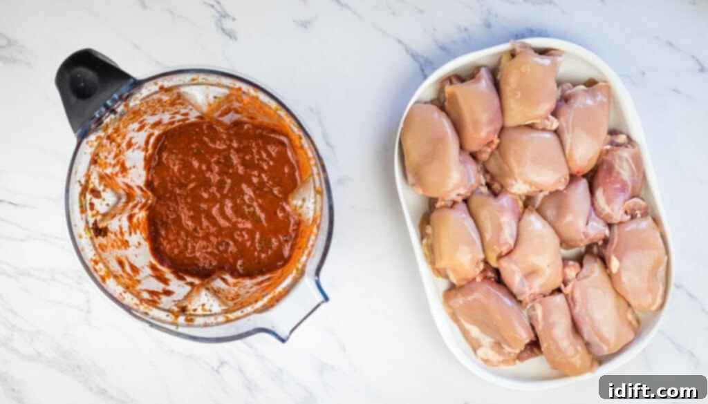 A blender filled with marinade ingredients next to chicken thighs, ready to be mixed.