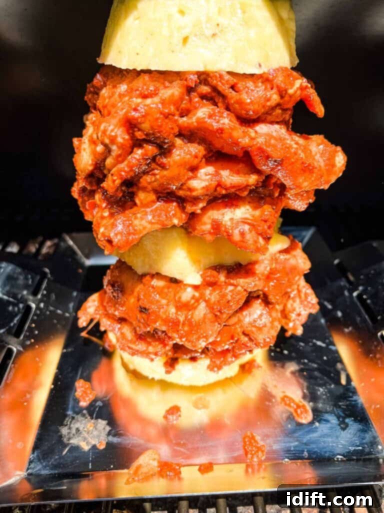 The assembled Chicken Al Pastor skewer cooking inside a smoker, filled with smoke.