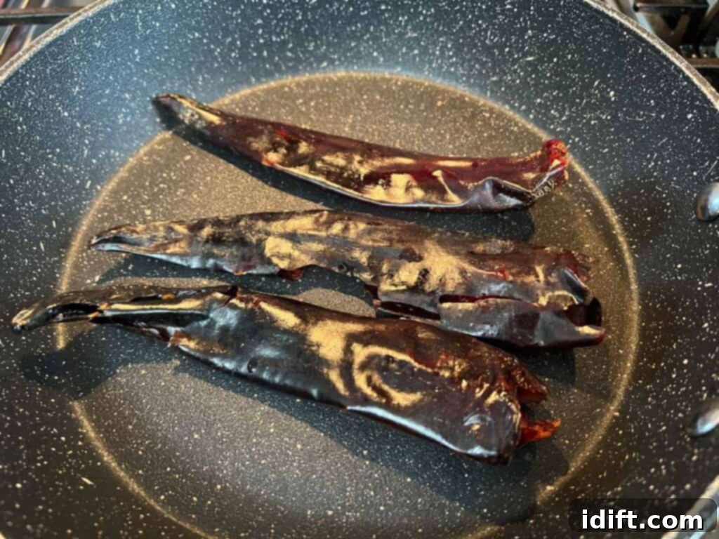 Guajillo chiles being toasted in a dry skillet to enhance their flavor.