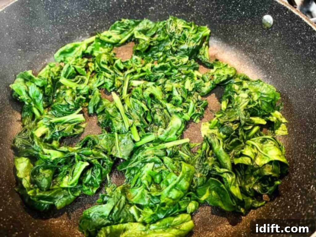 Velvet Mascarpone Spinach Your Ultimate Creamy Side 7 Spinach being sautéed in a skillet until wilted.
