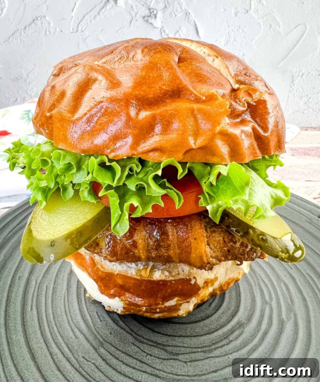 Perfectly cooked bacon-wrapped burger on a pretzel bun, ready to be enjoyed.